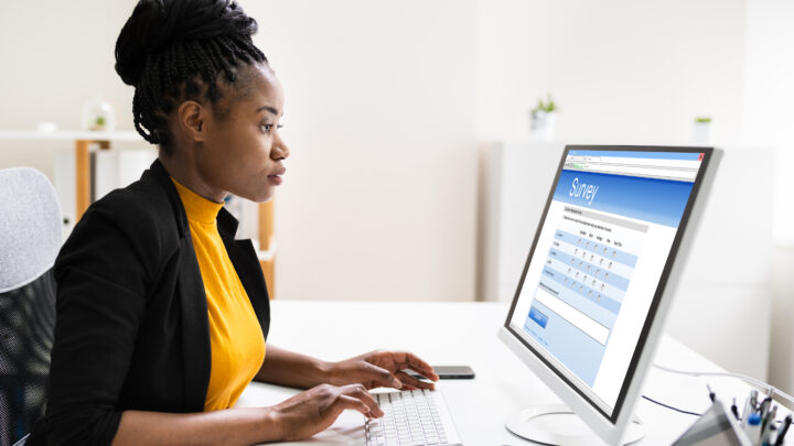 Female sitting at desk filling out a survey on computer